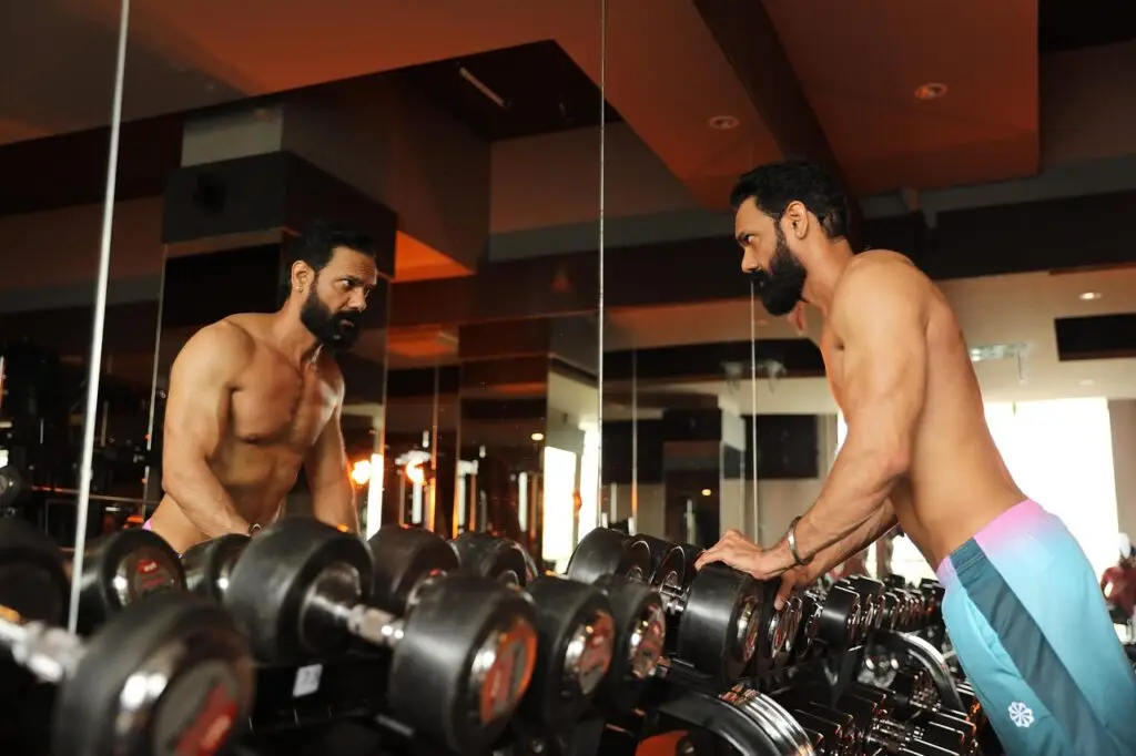 gympass wellhub homem fazendo academia se olhando no espelho